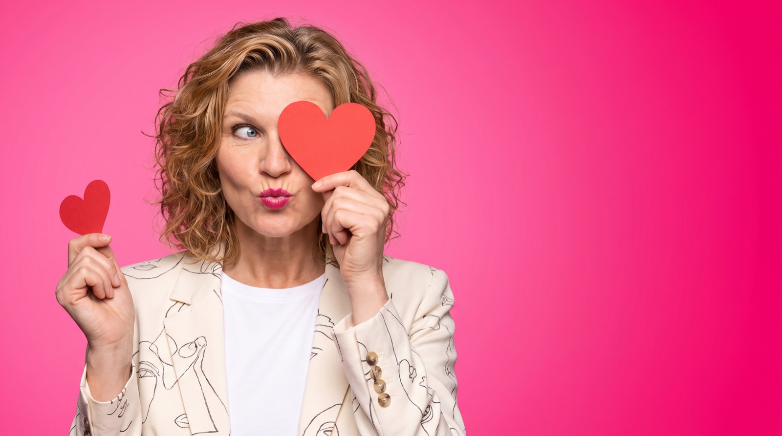 Patricia Heemskerk met een papieren hartje voor haar oog en een kusmond, op een roze achtergrond