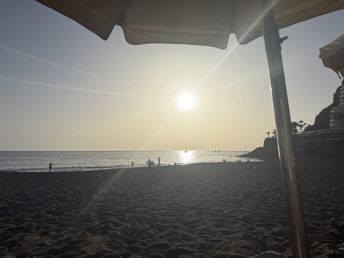 Zonsondergang boven zee, gezien vanaf het strand van Las Palmas onder een parasol