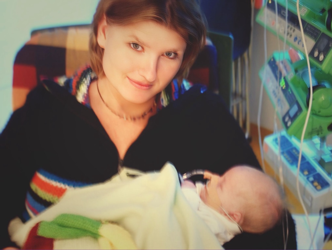 Patricia met baby Tycho in haar armen in het ziekenhuis, naast de monitors en infuuspompen