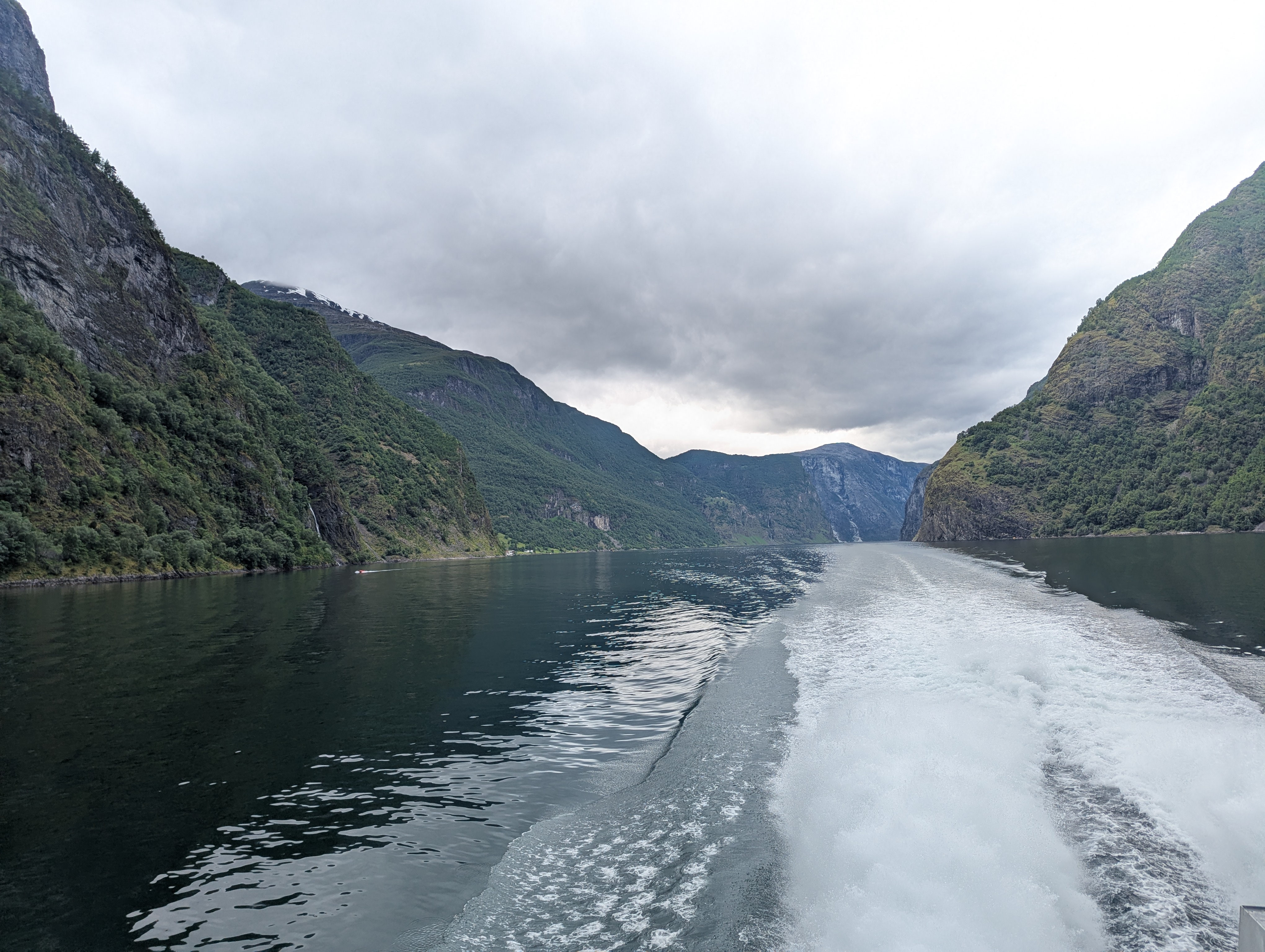 Ferry ride in the Norwegain fjords shown from the back of the ferry. Calm water with beautiful green and rocky hills. Ferry ride in the Norwegain fjords shown from the back of the ferry. Calm water with beautiful green and rocky hills.