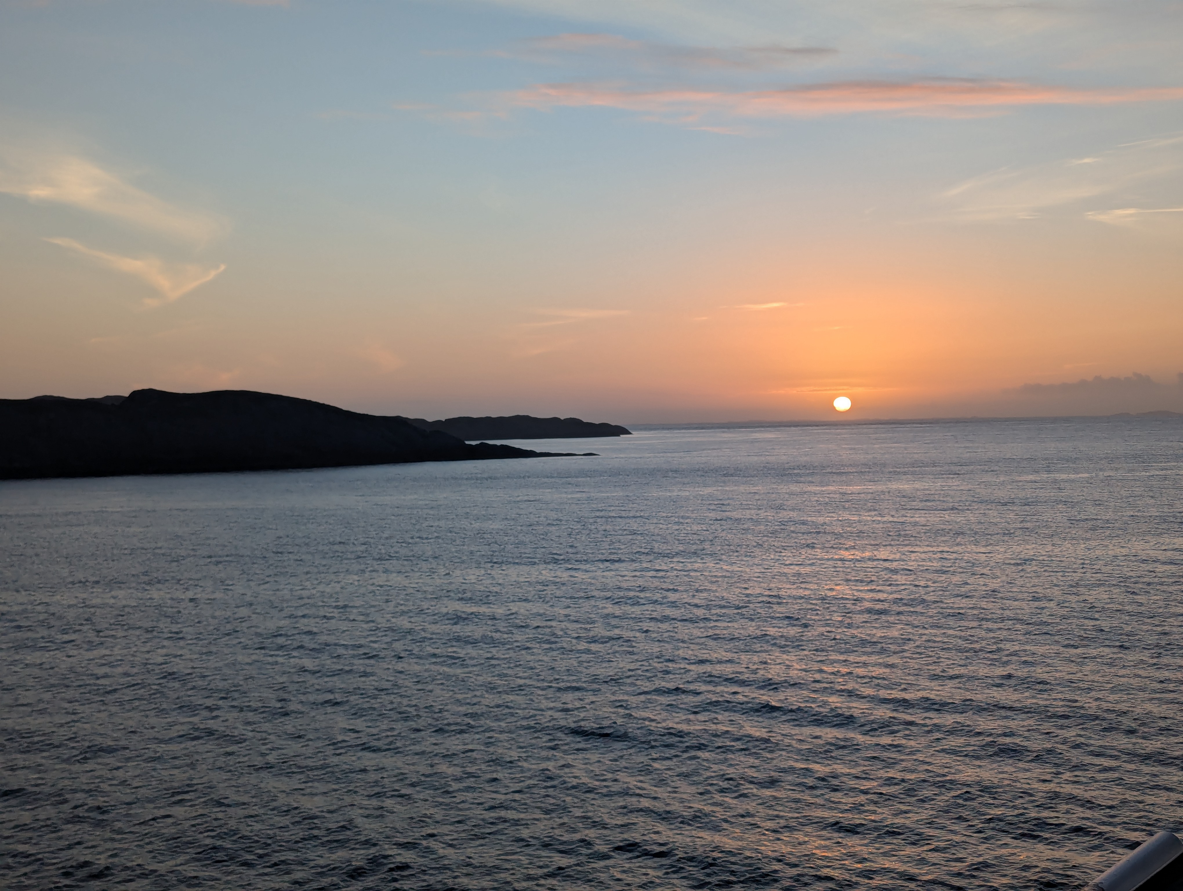 Sun setting on the horizon. Calm waters and an island in the distance. Sun setting on the horizon. Calm waters and an island in the distance.