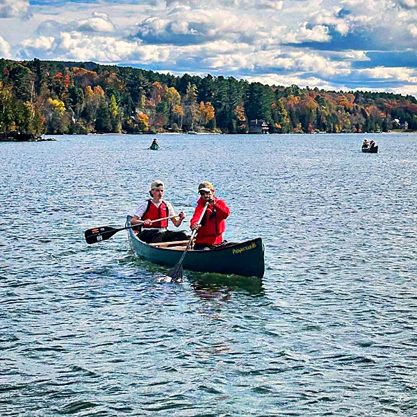 Two students in life jackets paddling a canoe on Lake Seymour in fall