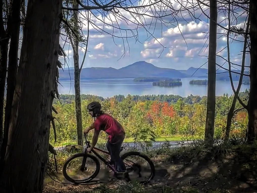 Mountain biker on a forest trail overlooking a lake and mountains