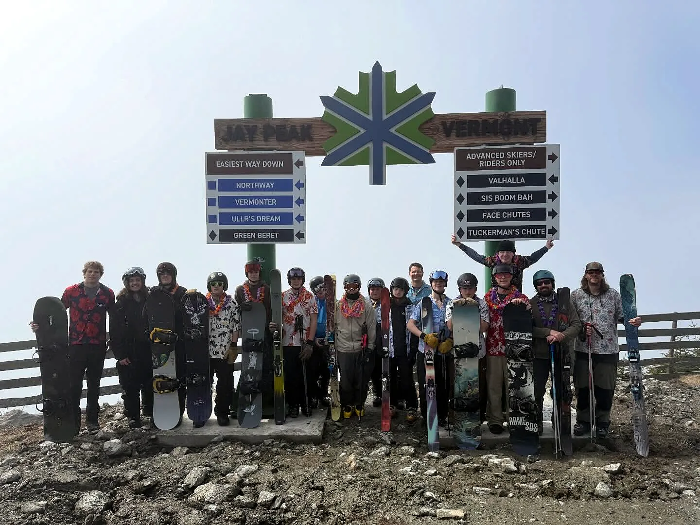 Kingdom Course students holding skis and snowboards beneath the Jay Peak summit trail sign