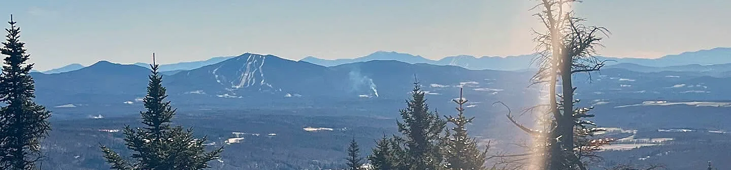 Snow-dusted ridgeline of Burke Mountain beyond frosted spruce