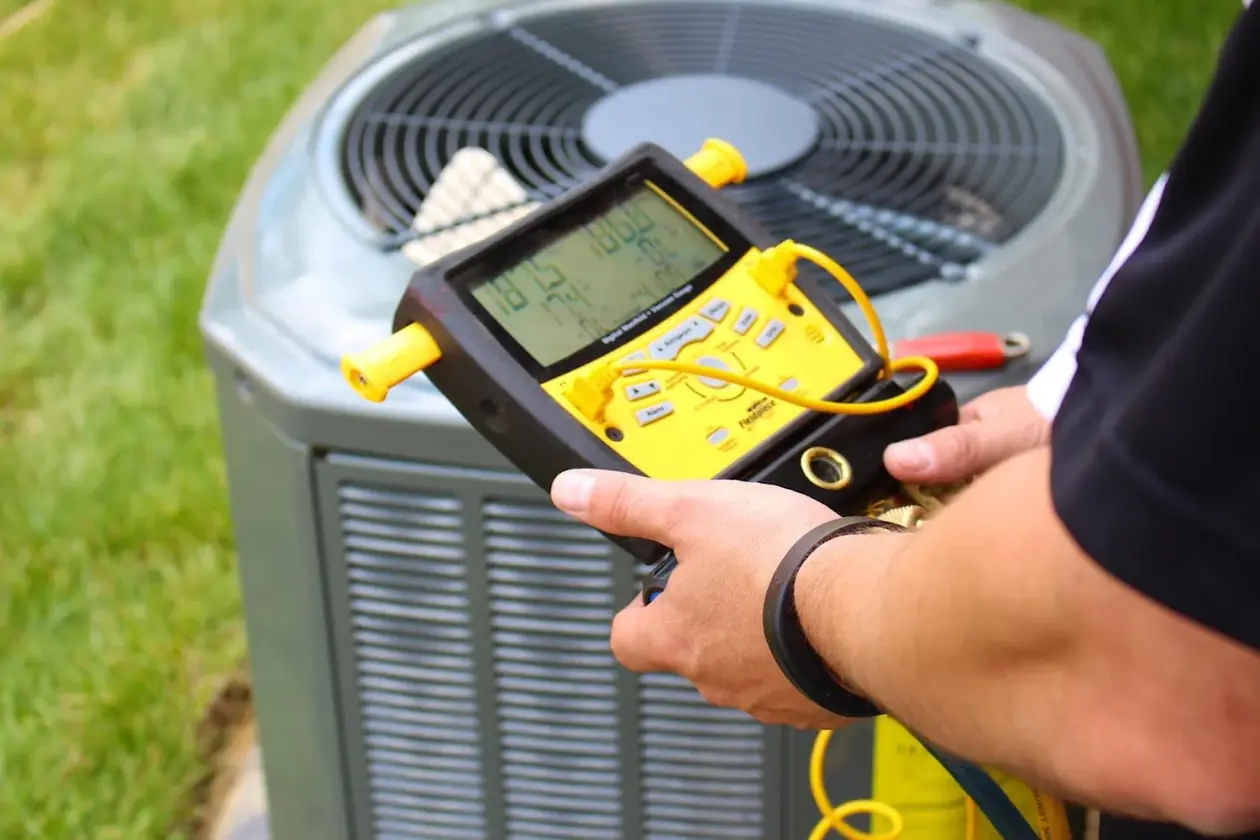 Technician checking refrigerant pressures on an outdoor AC unit