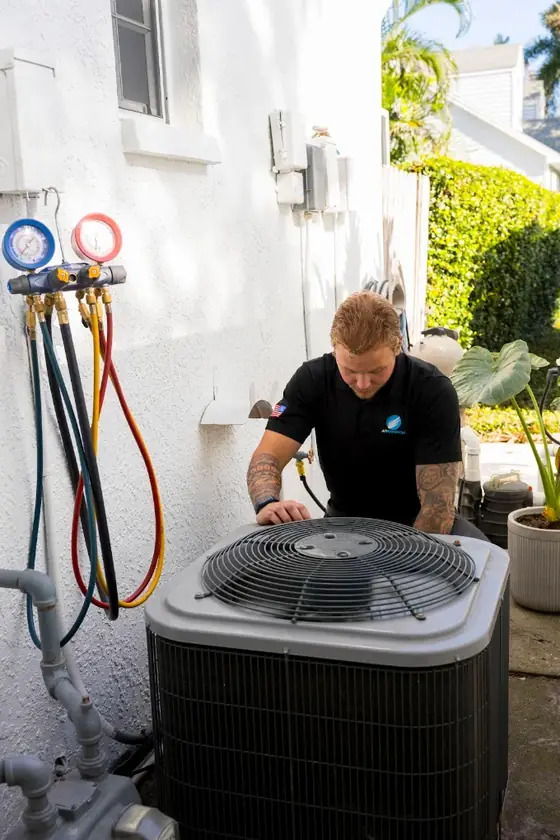 Technician servicing an outdoor AC condenser at a Tampa Bay home