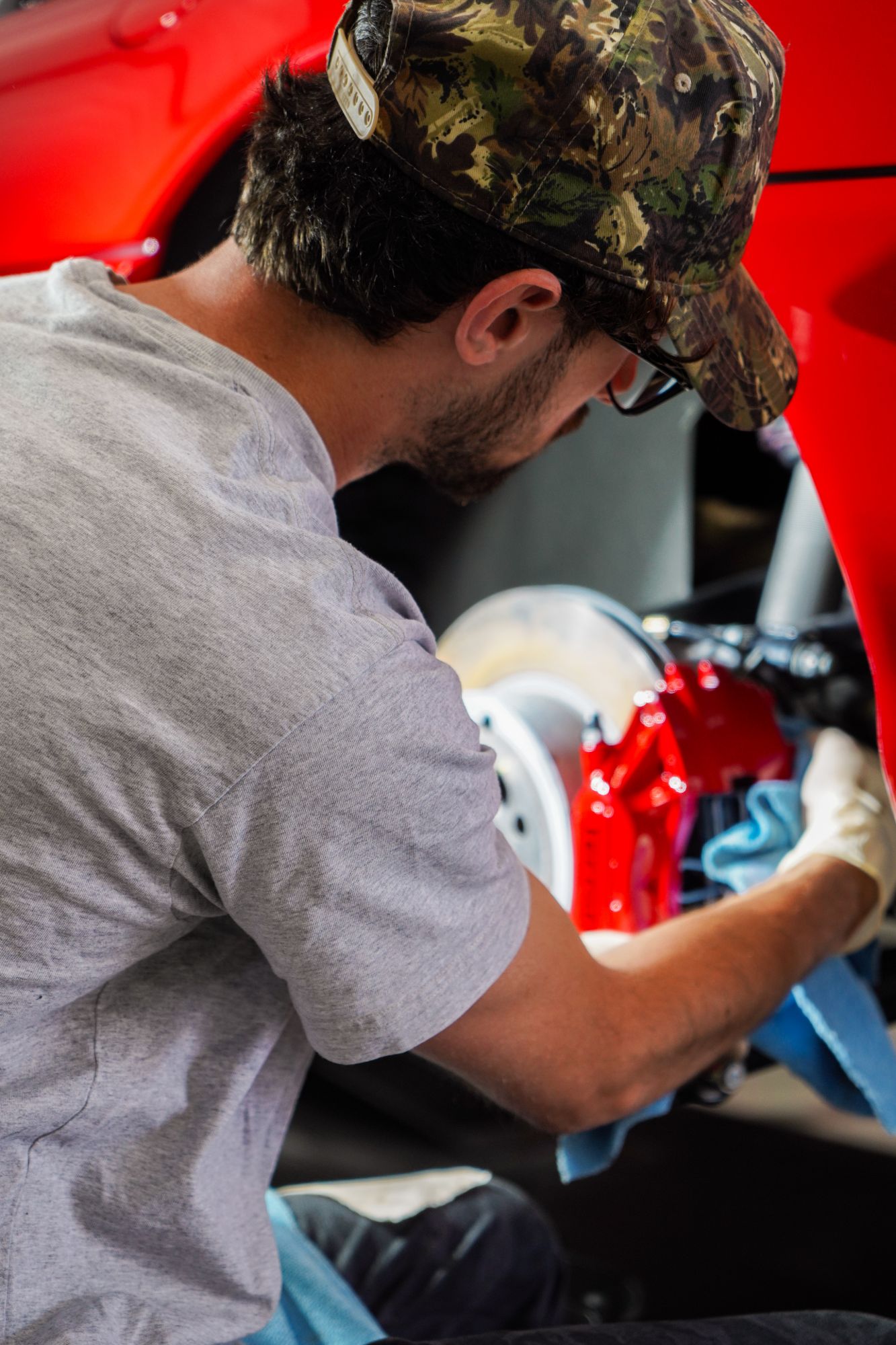 A detailer finishing a red brake caliper