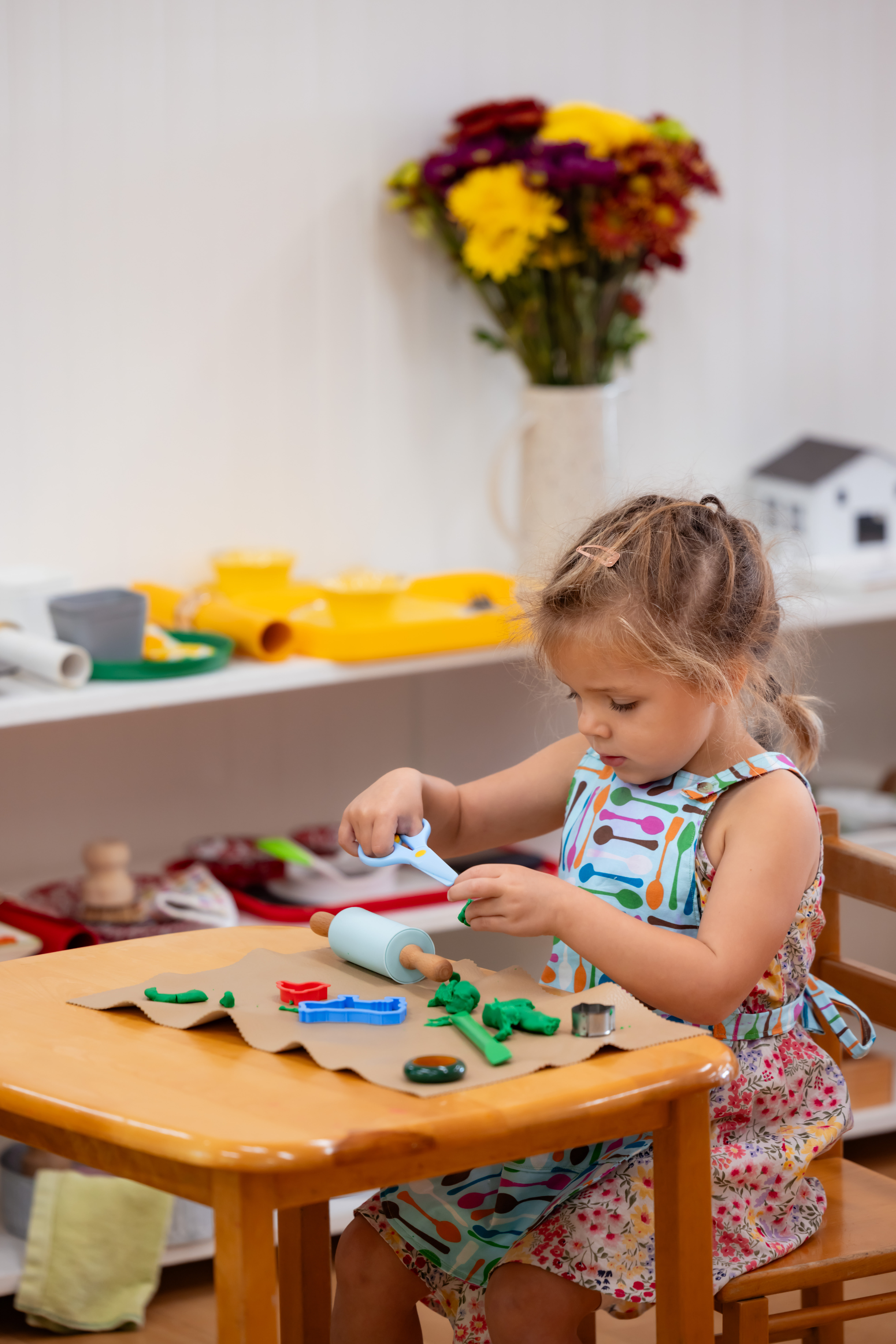 A primary student works with clay on a gray mat on a table