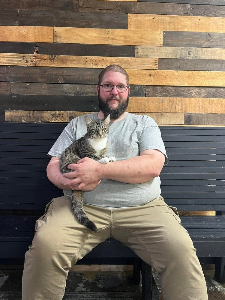 An adopter holding a tabby and white cat at Nine Lives