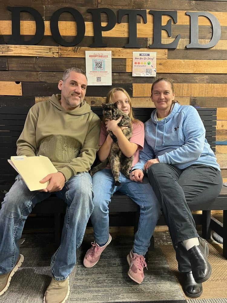 A family holding their adopted tabby cat at Nine Lives