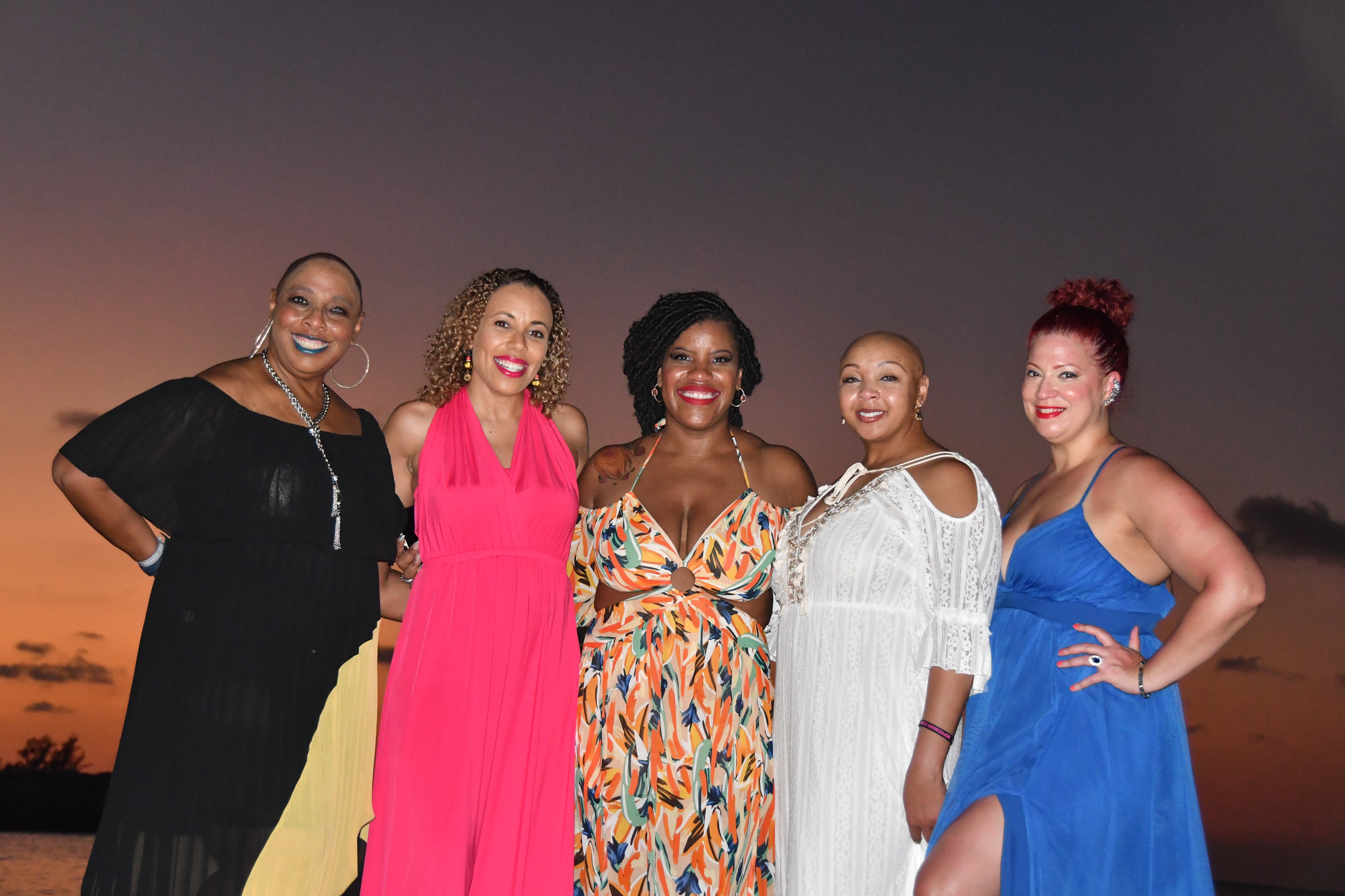Women posing together at sunset during the WANTED Woman Escape beach experience