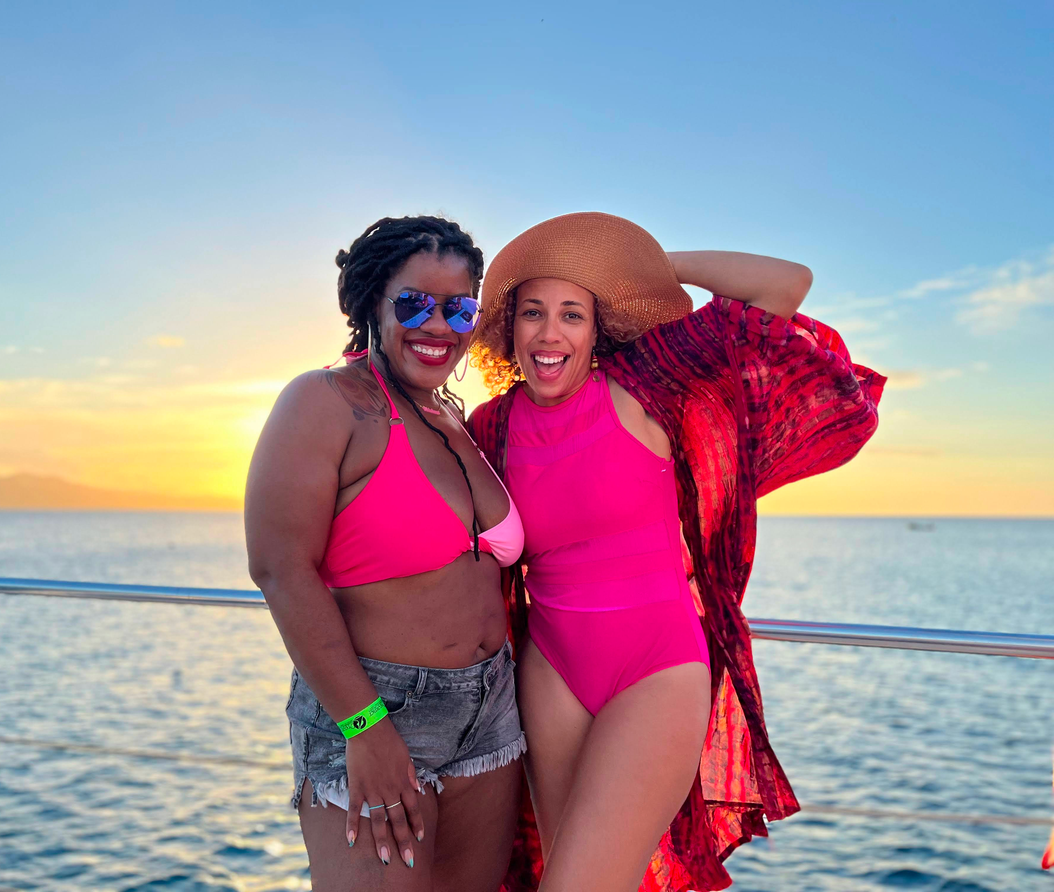 Women smiling in pink swimsuits by the ocean during the WANTED Woman Escape