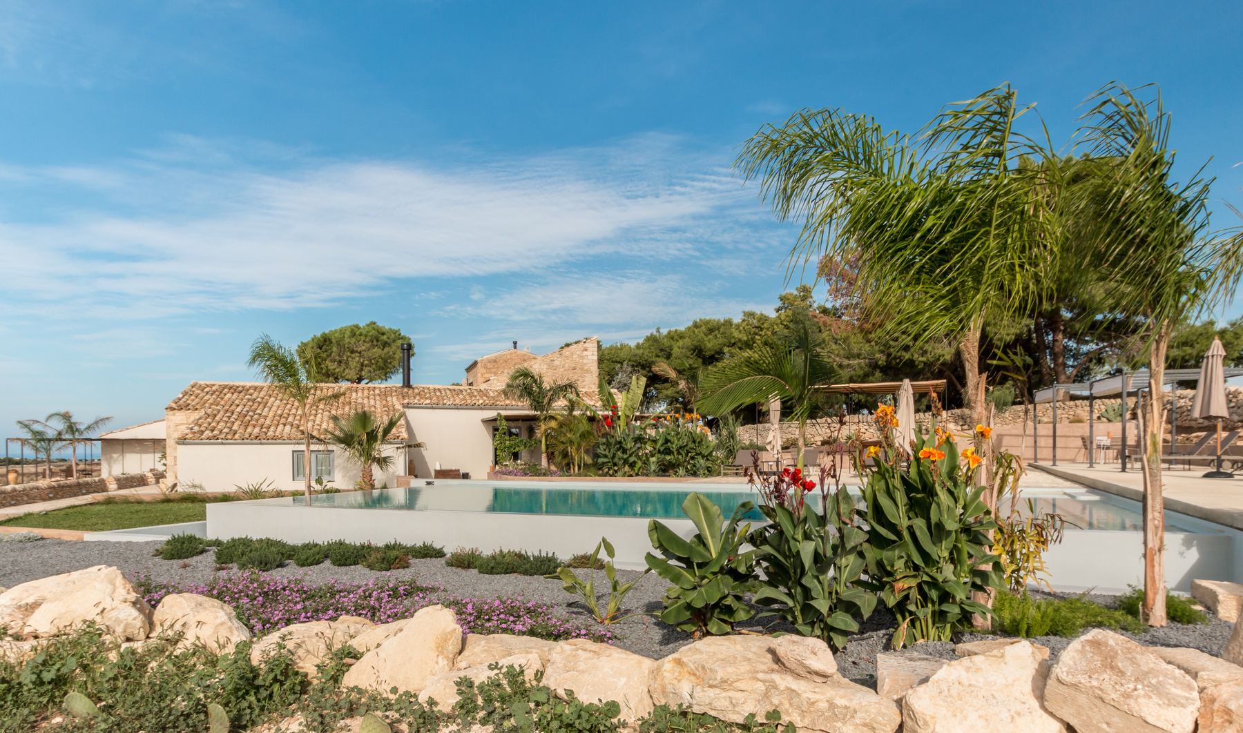 The pool and farmhouse among palms and flowers