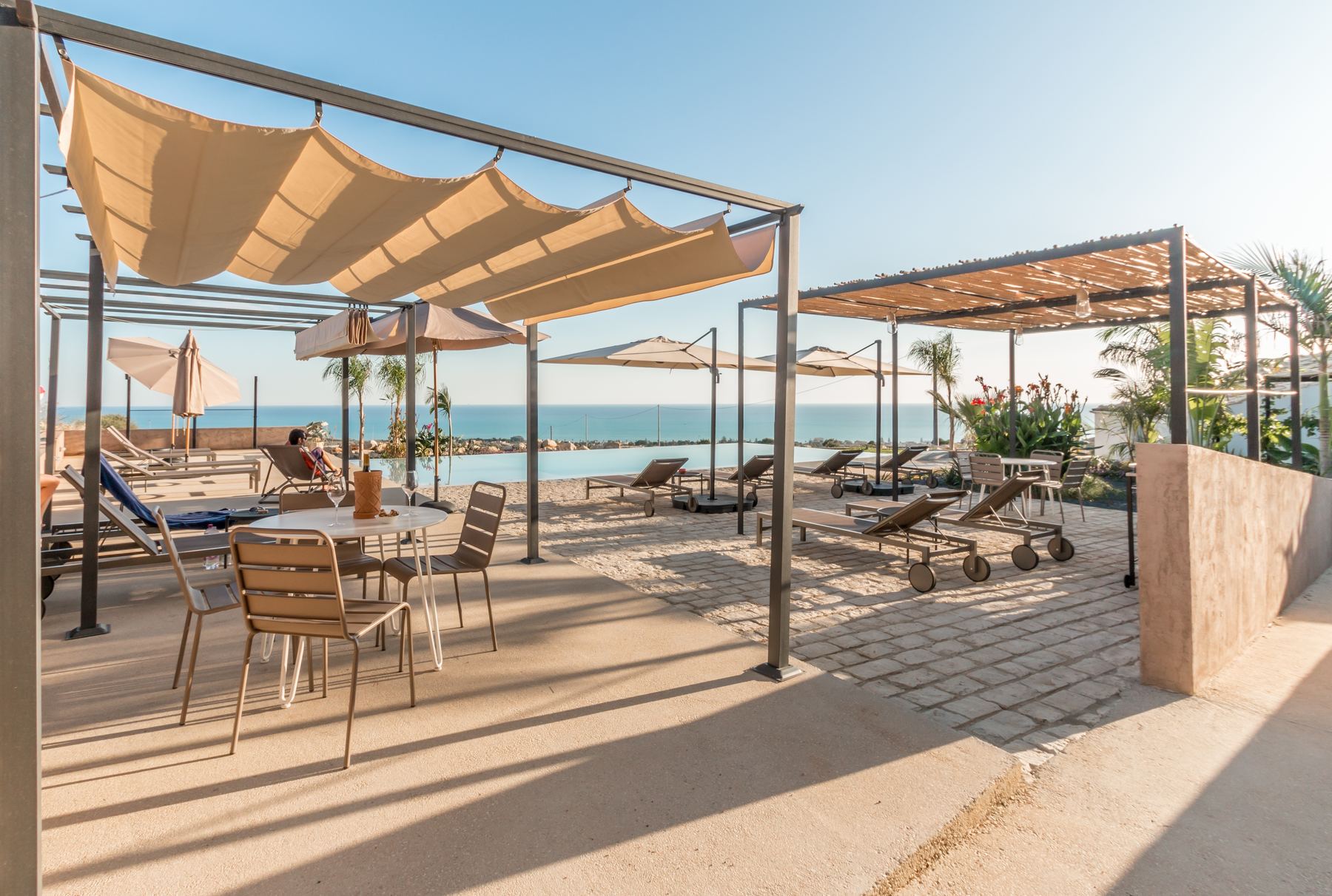 Shaded terrace beside the infinity pool, sea beyond