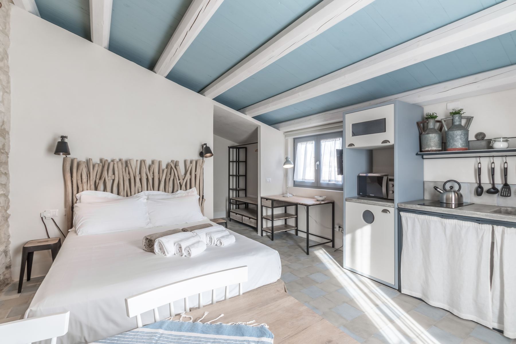 A room with a driftwood headboard and blue ceiling