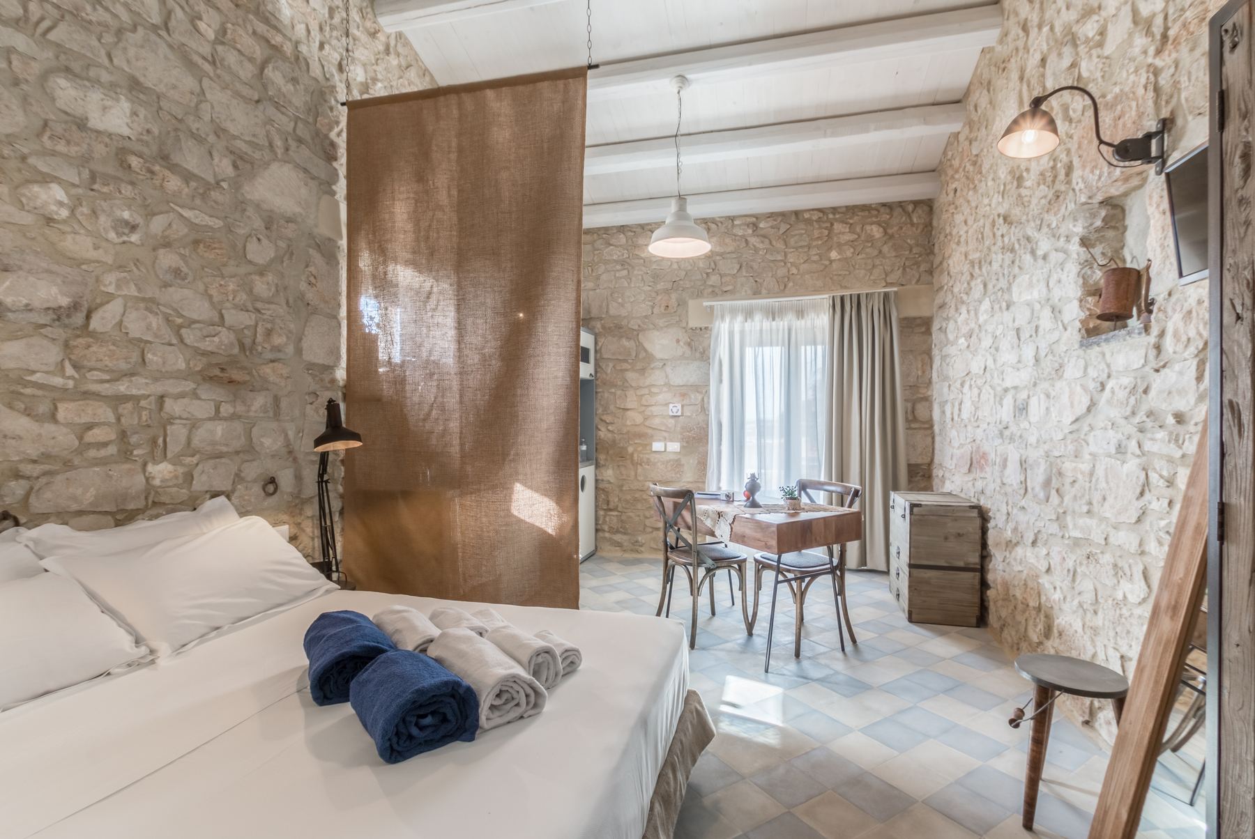 A stone-walled room with a linen screen and small table