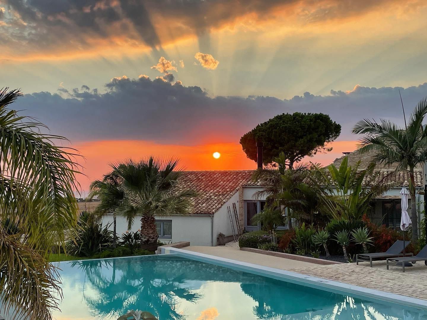 Sun rays over the farmhouse and pool at sunset