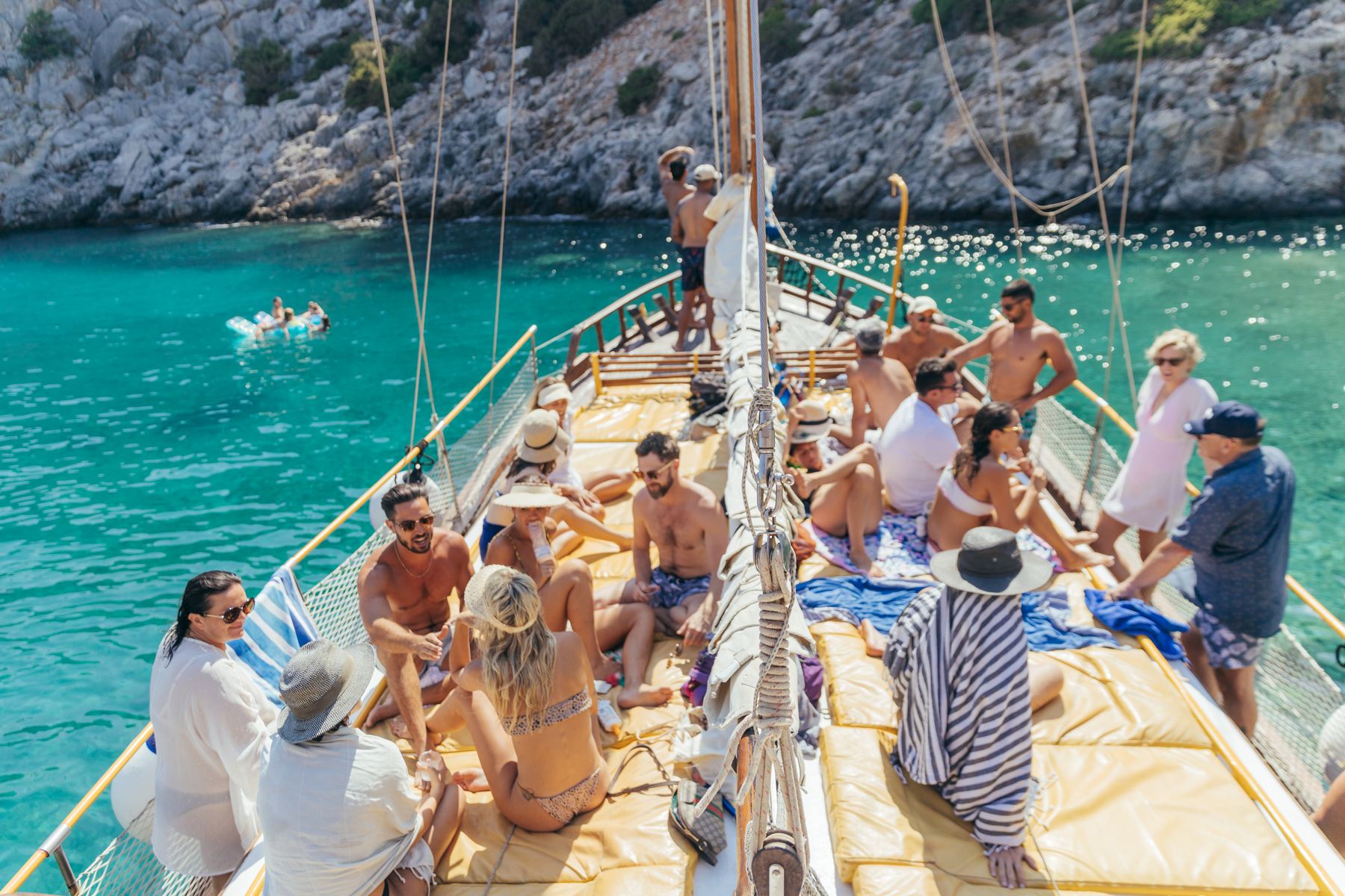 Guests relaxing on a wooden boat in a turquoise bay