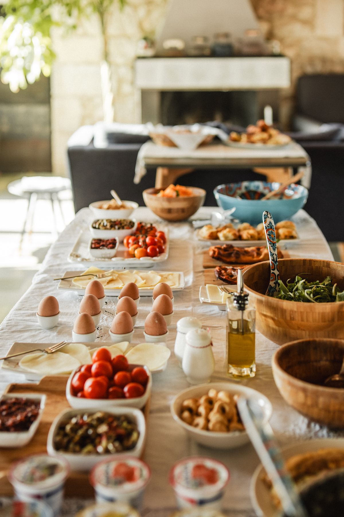 A long brunch table of eggs, tomatoes, cheese and salads