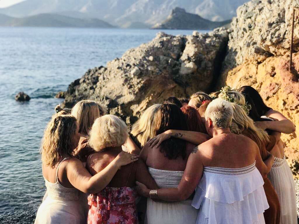 A group embracing on the rocks above the sea