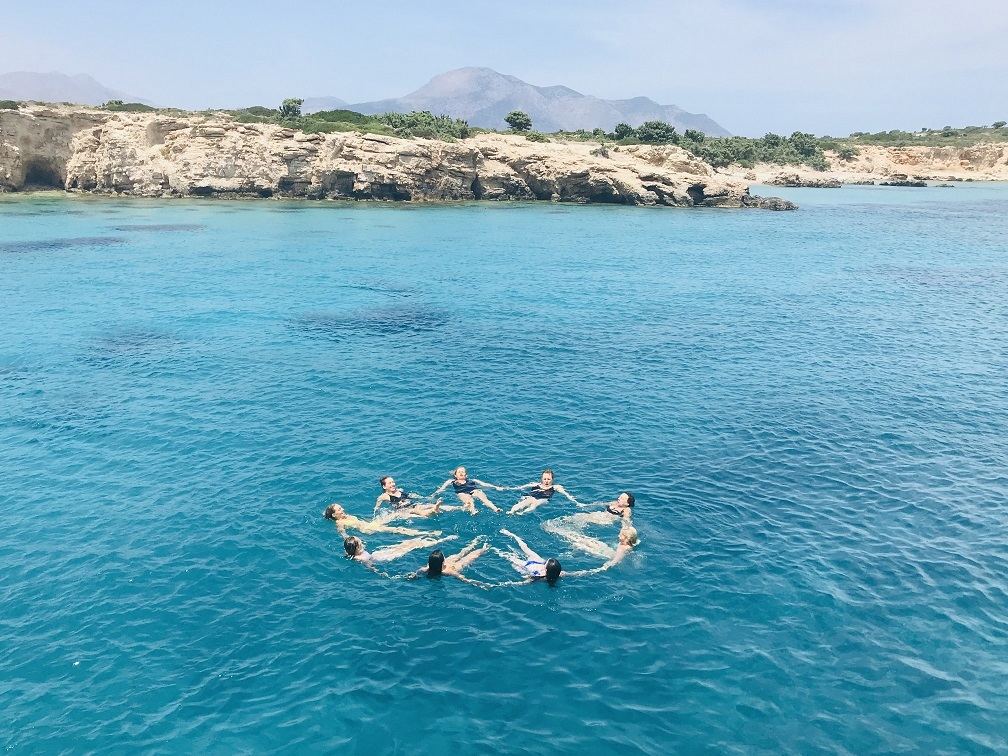 A circle of women floating hand in hand in the sea