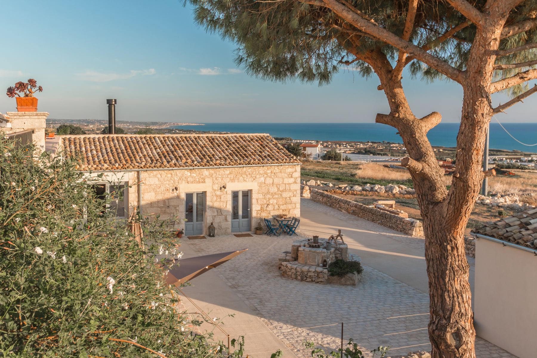 The stone courtyard and old well, with the sea beyond
