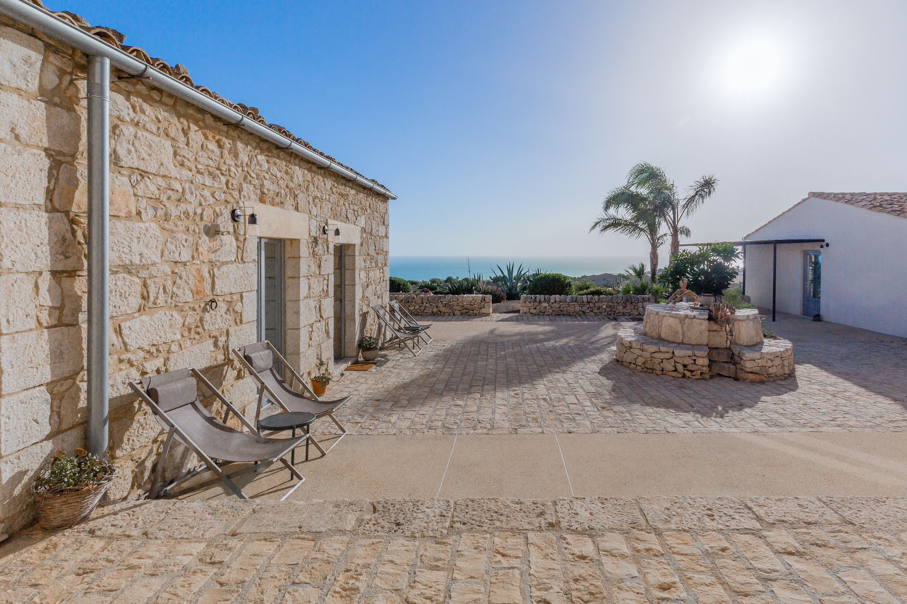 The stone courtyard and old well, with the sea beyond
