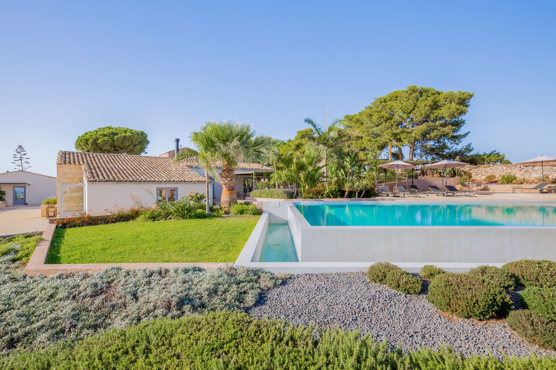 The farmhouse, lawn and infinity pool on its terrace