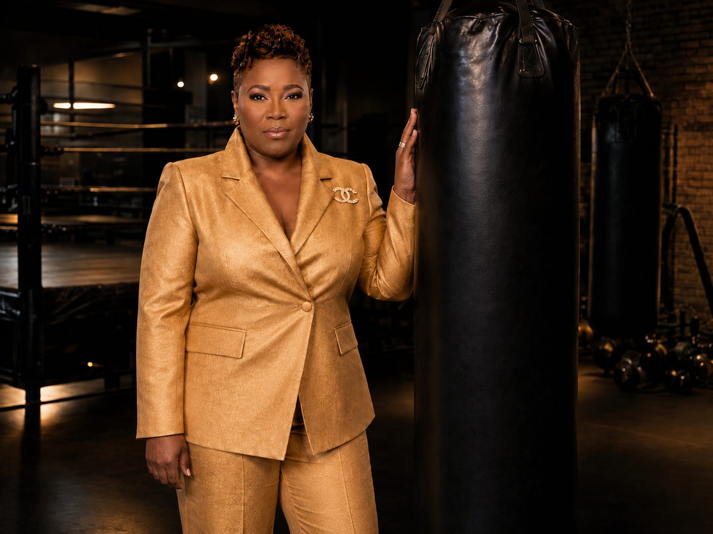 Mary H. Davis in gold suit next to boxing bag — Women's Level Up Network founder