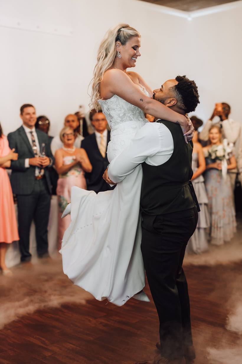 Groom lifting his bride on the dance floor while their guests look on