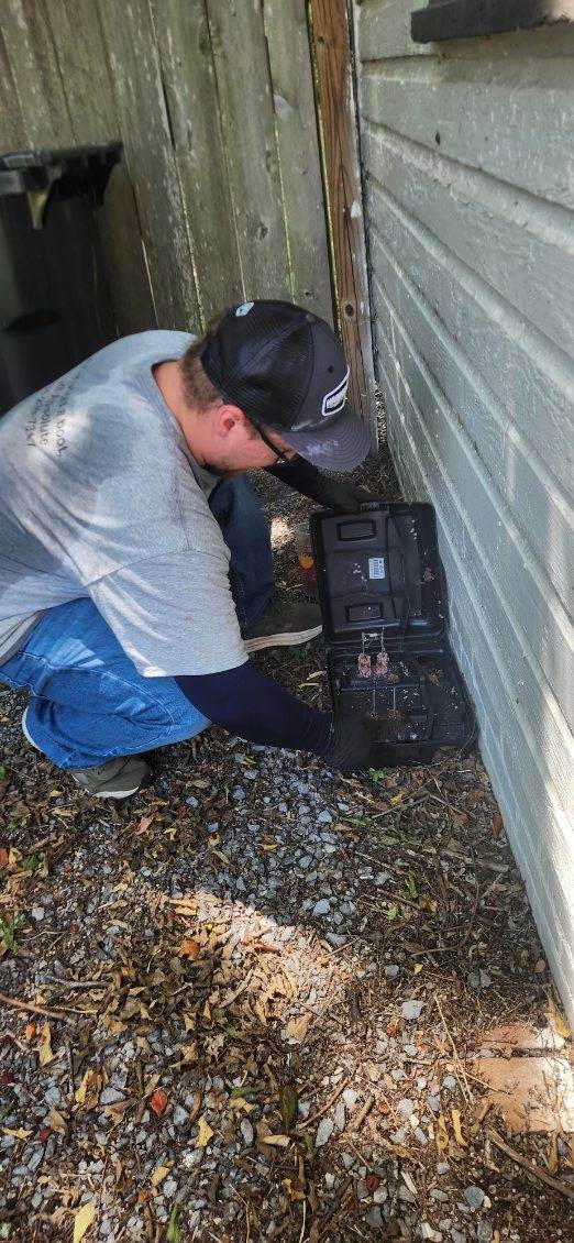Rodent control technician inspecting the exterior and crawl space of a Central Alabama home for potential entry points
