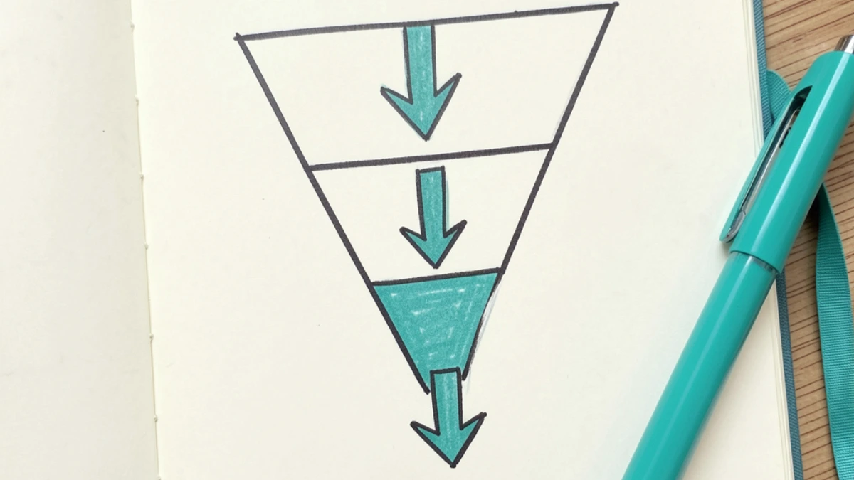 Overhead flat lay of a notebook with a hand-drawn tripwire funnel diagram and teal pen