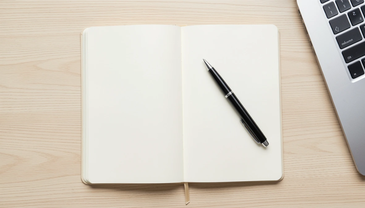 Overhead flatlay of clean desk with open blank notebook and pen representing Kajabi vs Kartra pricing comparison for online business owners
