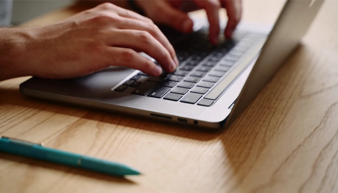 Close-up of hands at laptop writing a blog post - best tools for blogging as a small business owner