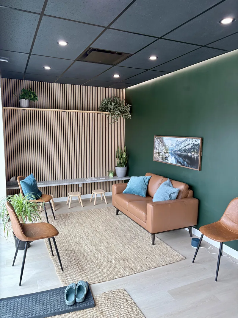 Waiting area at Achieve Movement Health Clinic in Simcoe, with a leather couch, oak slat wall and a mountain print