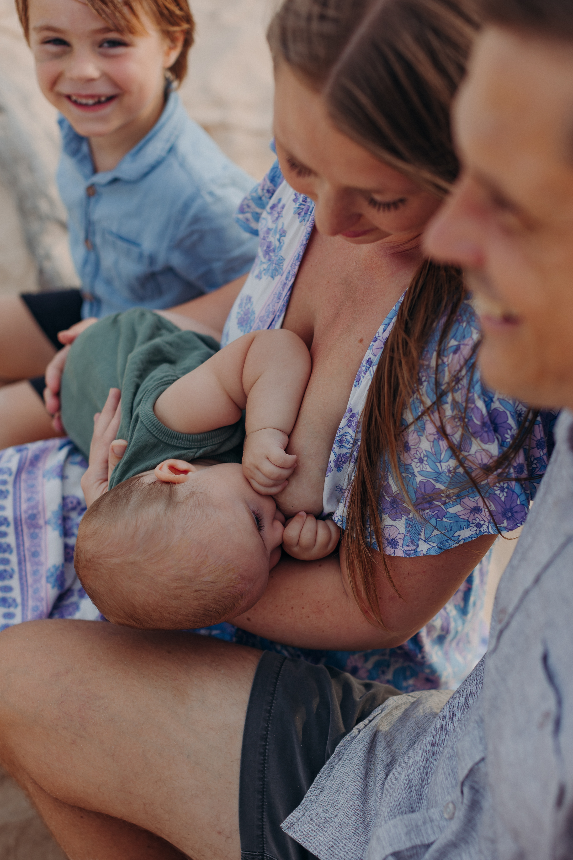 Izabelle breastfeeding her baby on the beach with her son beside her