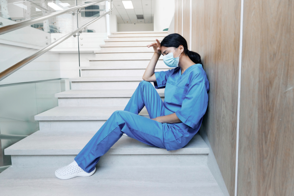 nurse sitting on stairs clearly overwhelmed
