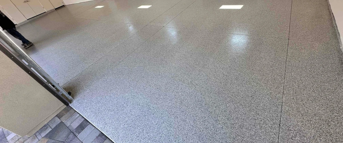 Wide-angle view of a garage floor finished with a speckled epoxy flake coating. Wide-angle view of a garage floor finished with a speckled epoxy flake coating.