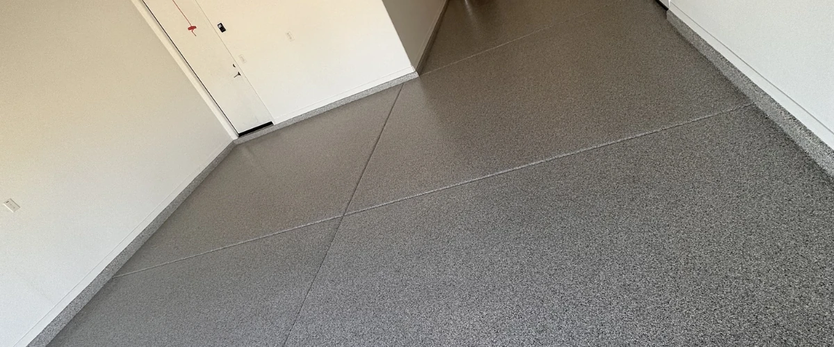 Wide-angle view of a garage floor finished with a speckled epoxy flake coating.