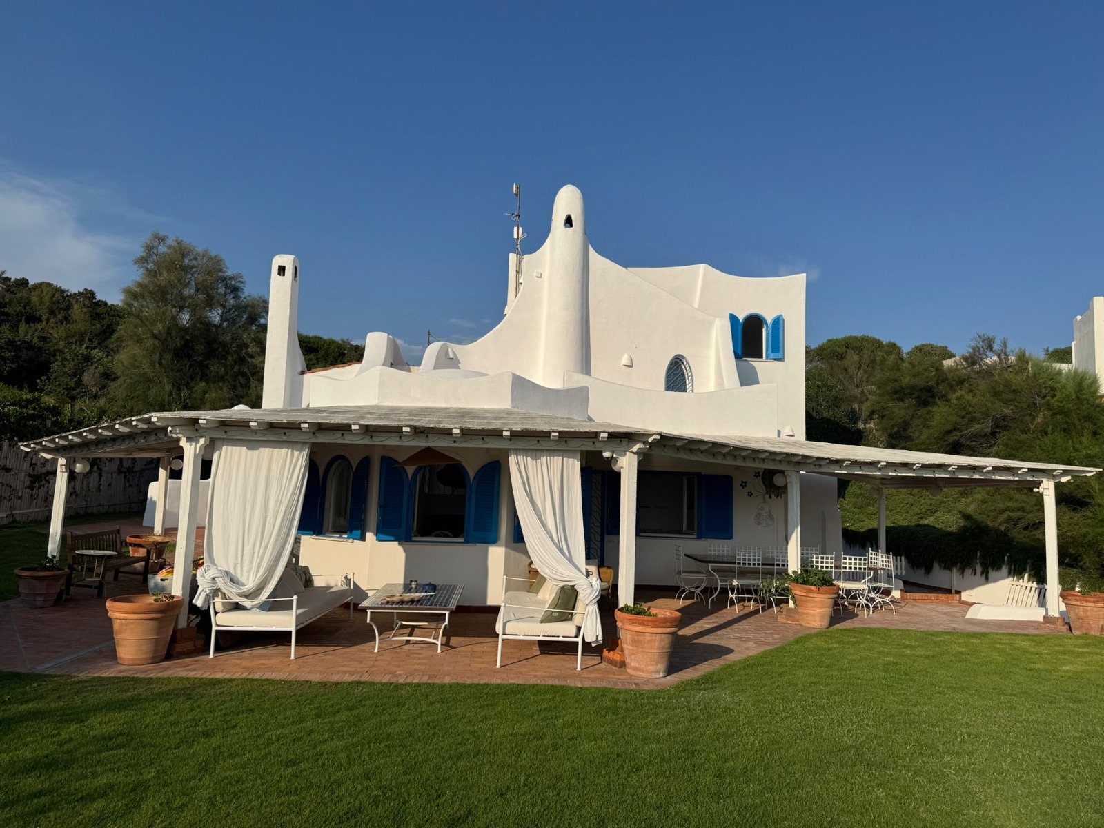 Villa mediterranea bianca con persiane blu, pergolato e giardino sul mare — Sabaudia