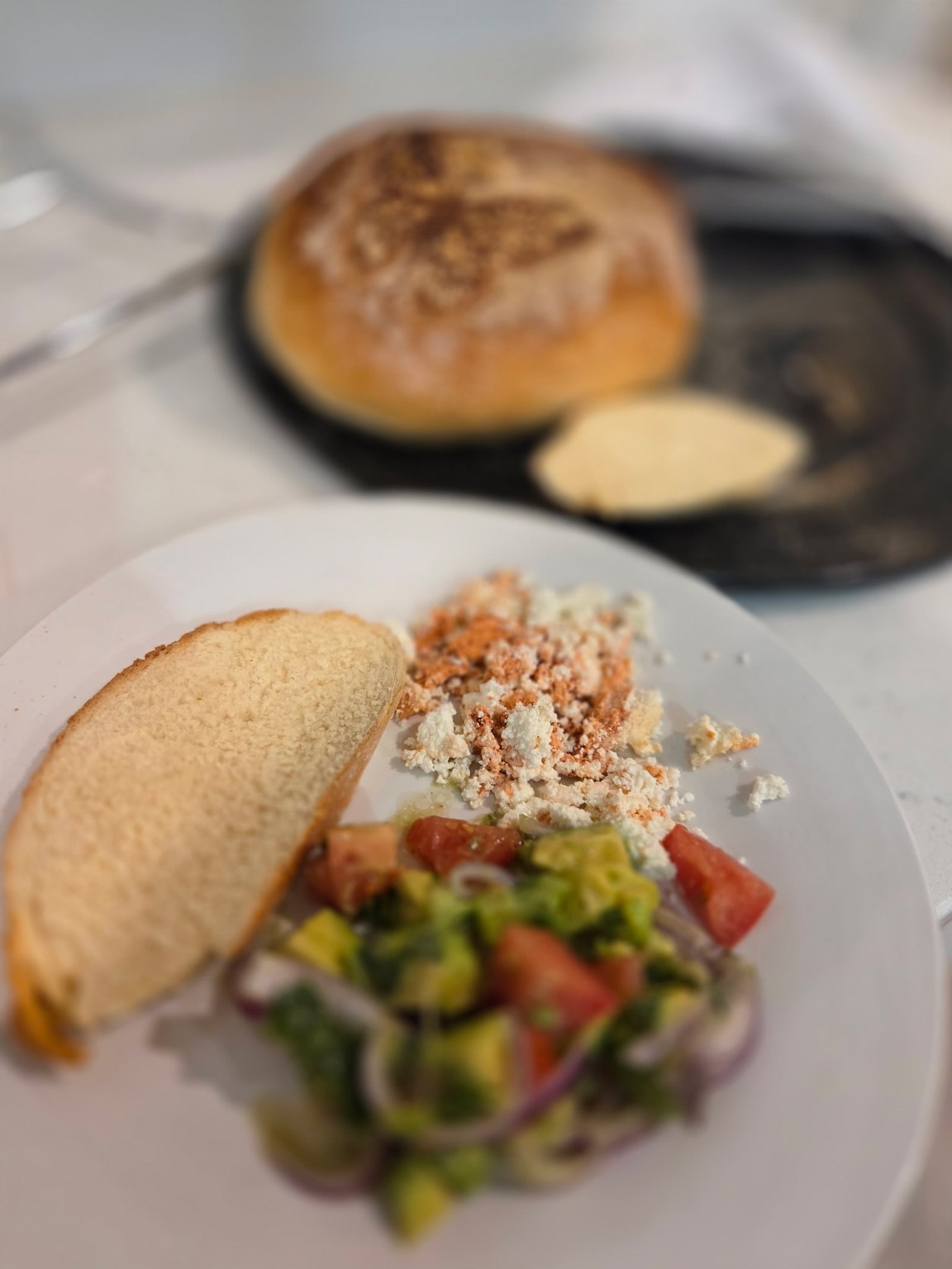 Homemade rustic whey bread with queso fresco, avocado tomato salad, and toasted sandwich ingredients on kitchen counter Homemade rustic whey bread with queso fresco, avocado tomato salad, and toasted sandwich ingredients on kitchen counter