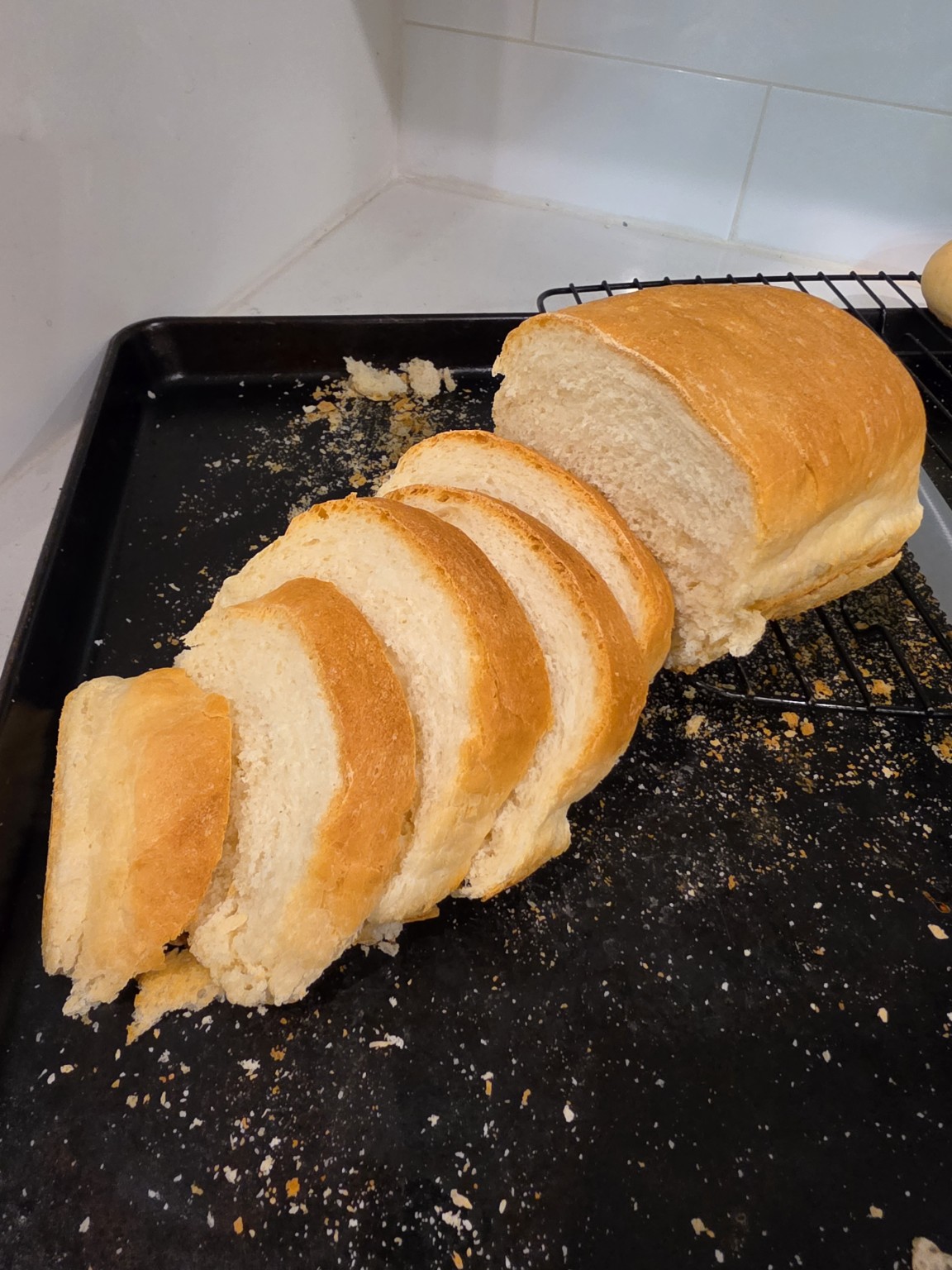 Fresh homemade sandwich bread sliced on a cooling rack.