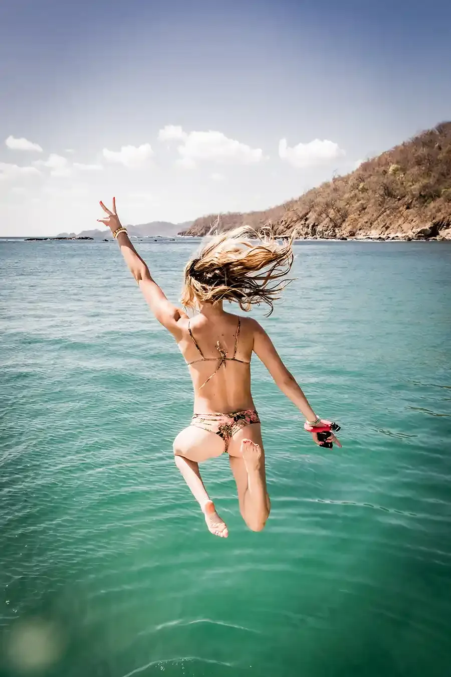 Woman jumping into turquoise water in Nicaragua
