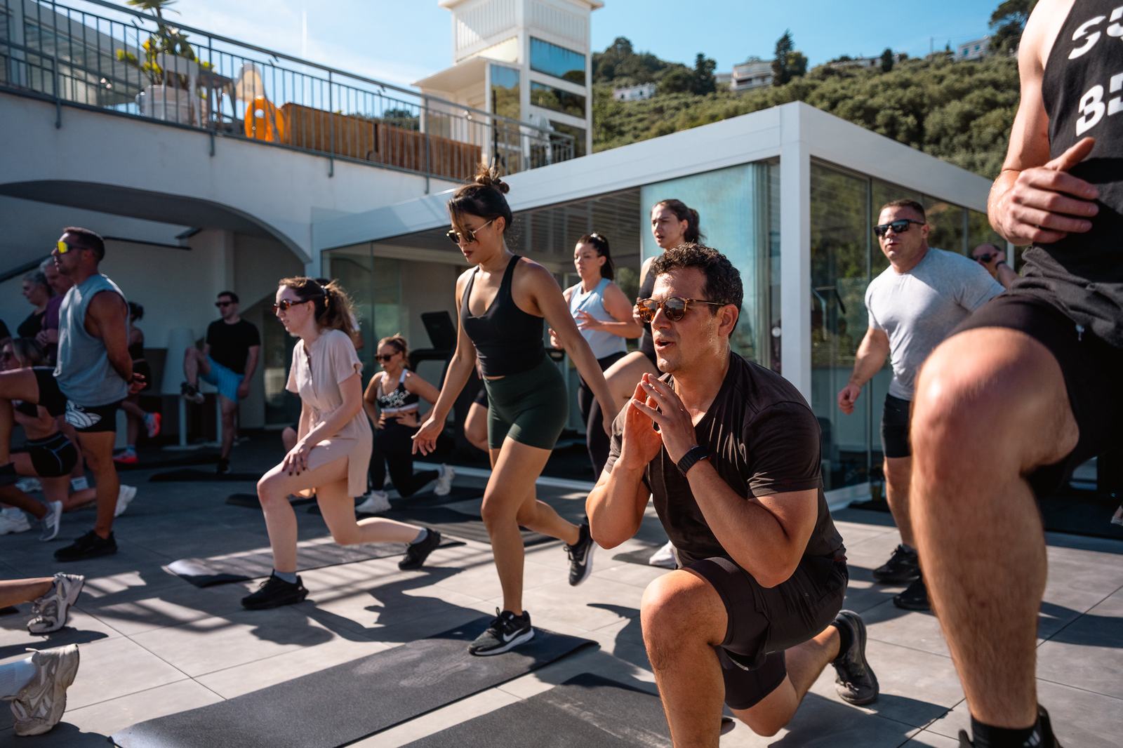 A group doing lunges together on a terrace above the sea