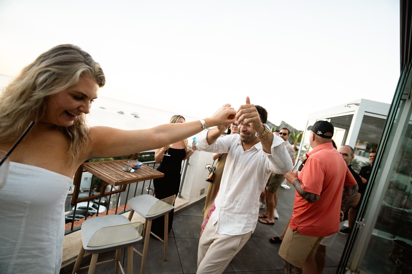 A group of travelers dancing on a terrace at sunset