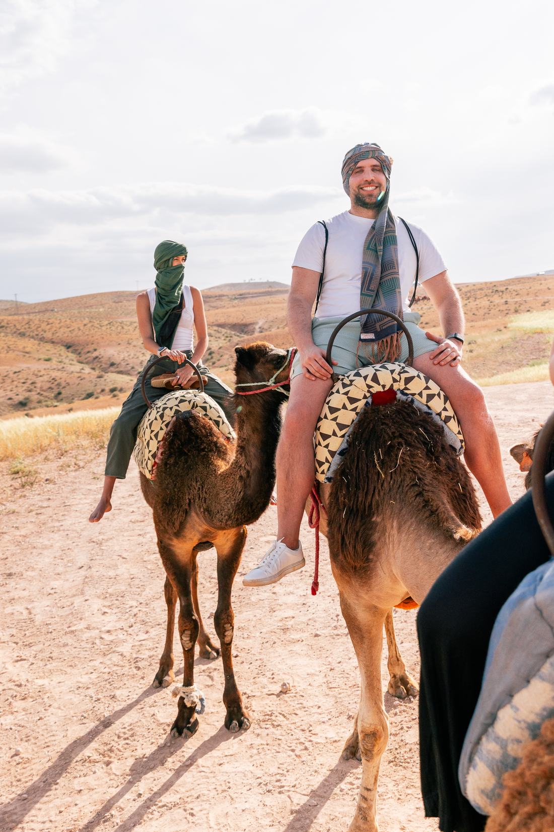 Two travelers riding camels in Morocco