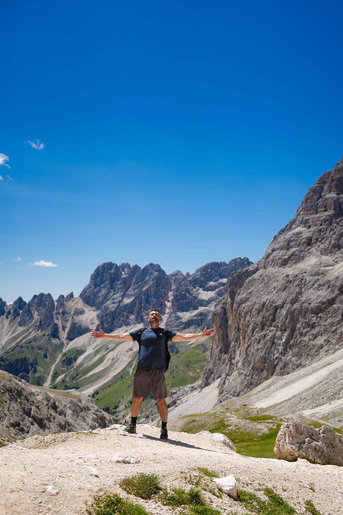 A hiker with arms outstretched in front of Dolomite peaks