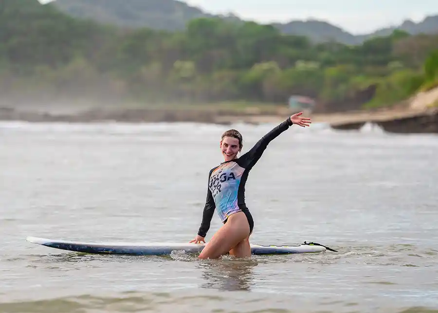 Woman sitting on a surfboard, arms out