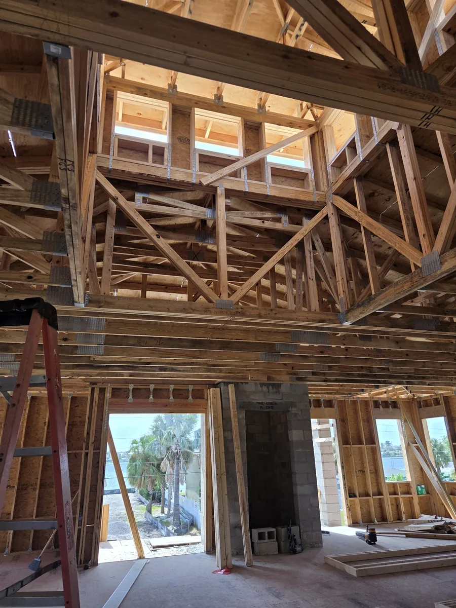 Inside a house under construction: timber framing and an opening toward the water